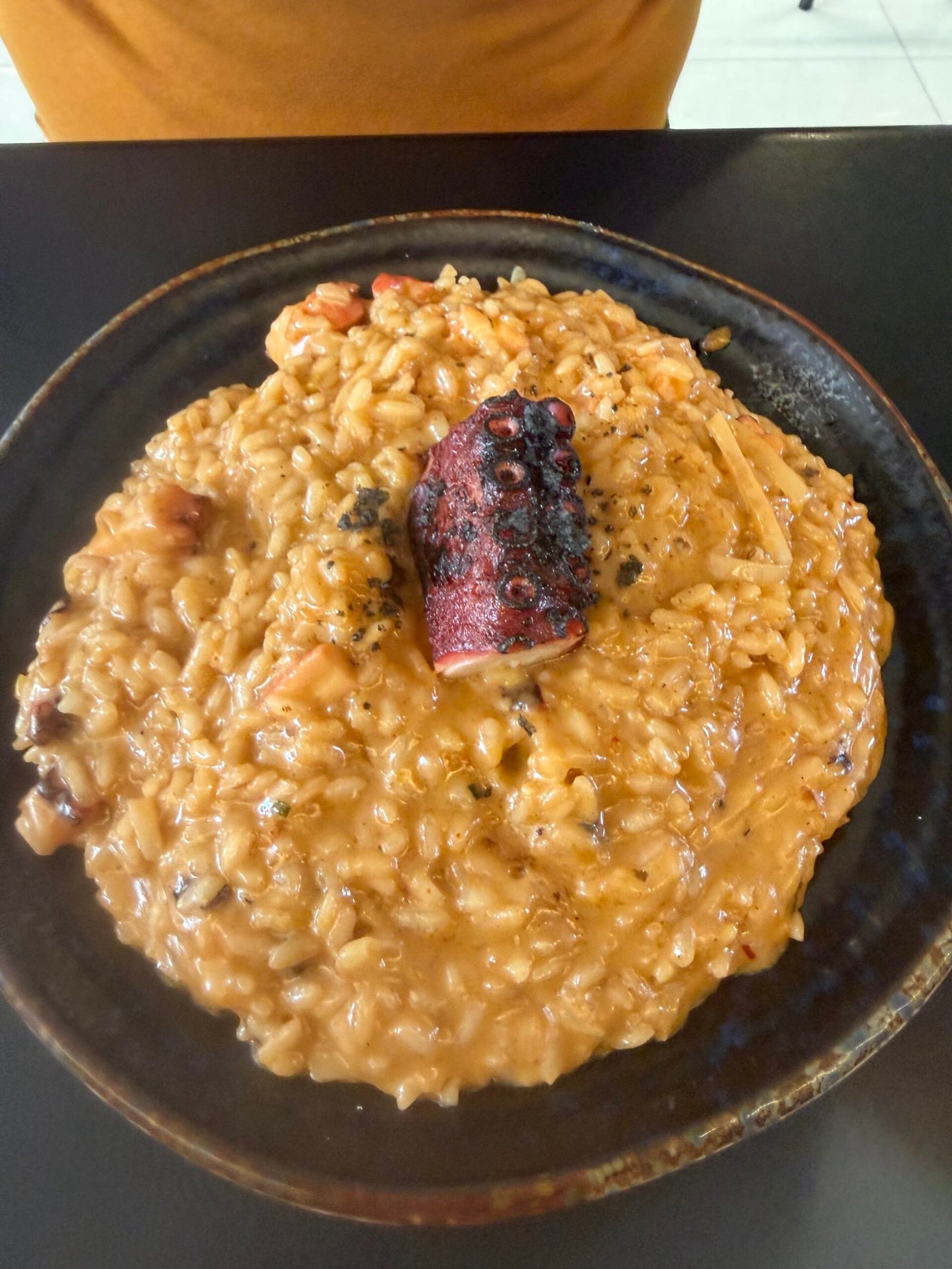 Risotto cremoso en plato negro en The Rumors Gastrobar, Tegueste